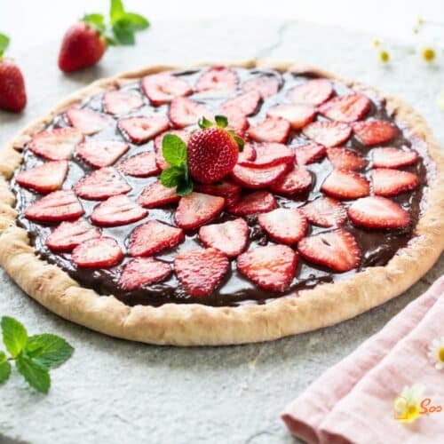 Pizza dessert chocolat fraise sur planche ronde avec fleurs et feuilles de menthe