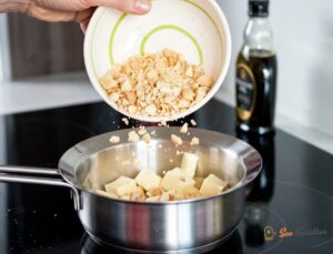 Trois carrés de biscuits caramel macadamia empilés sur ardoise noire avec noix éparpillées autour